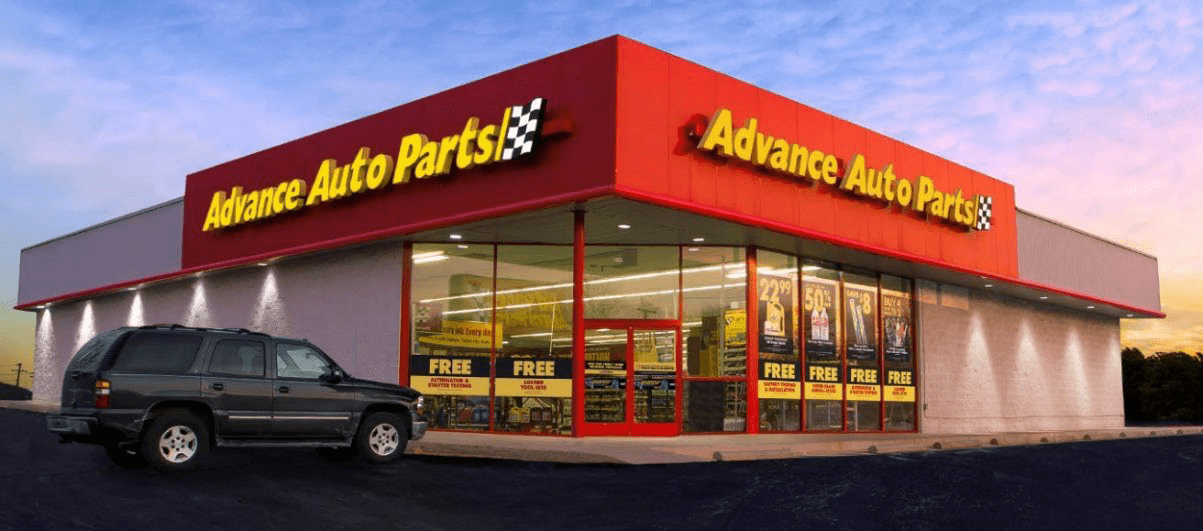 A car parked in front of a red auto parts store.