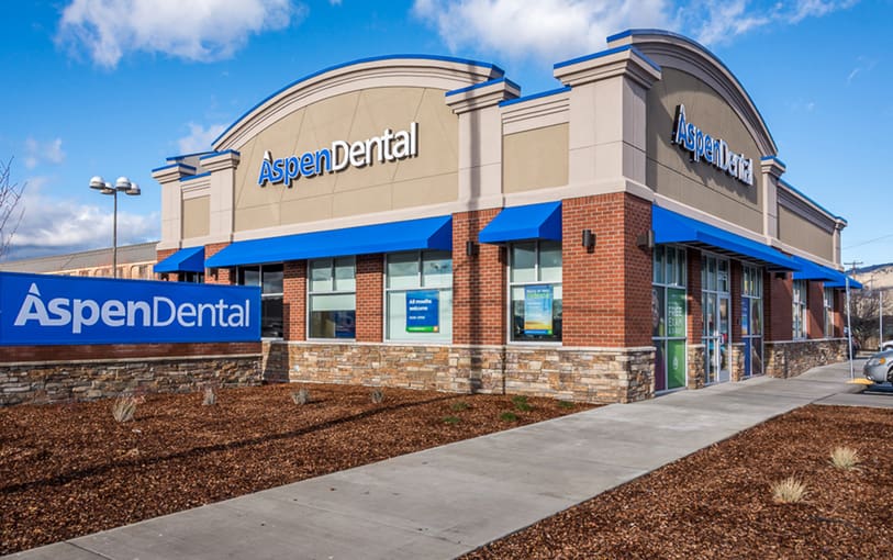 A dental office with blue awnings and a sidewalk.