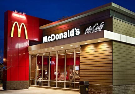 A mcdonald 's restaurant with many people sitting at the tables.