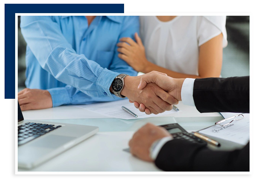 A man shaking hands with another person in front of two other people.